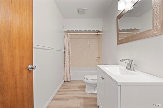 bathroom featuring visible vents, toilet, wood finished floors, shower / tub combo with curtain, and vanity