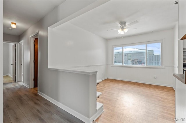 unfurnished room featuring a ceiling fan, baseboards, and wood finished floors