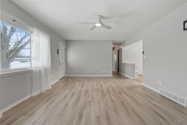 unfurnished living room with ceiling fan, light wood-style flooring, visible vents, and baseboards