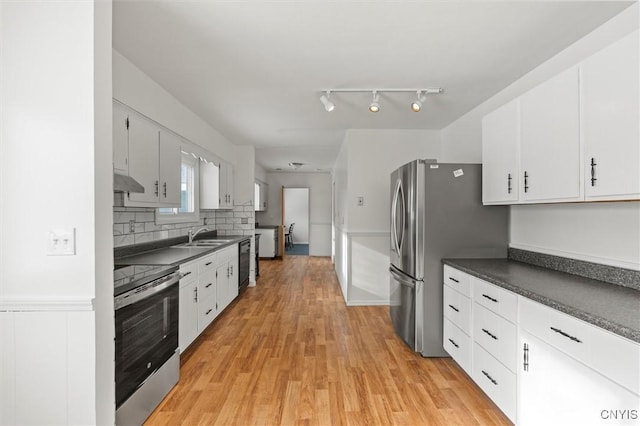 kitchen with stainless steel appliances, dark countertops, backsplash, white cabinetry, and light wood-type flooring