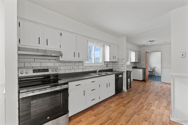 kitchen featuring under cabinet range hood, a sink, black dishwasher, electric stove, and dark countertops