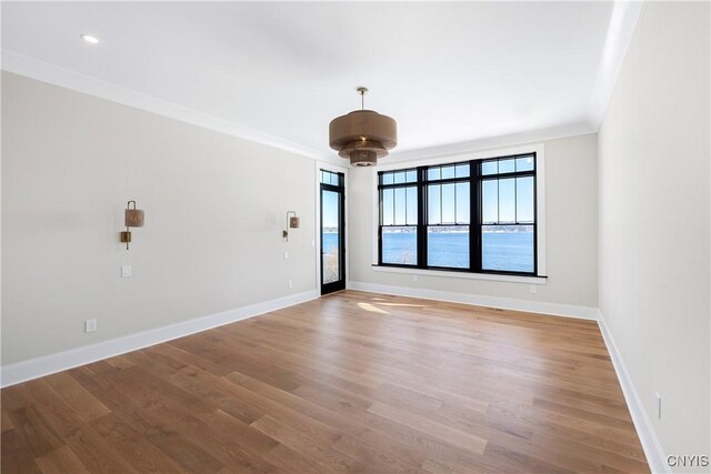 empty room featuring ornamental molding, baseboards, and wood finished floors