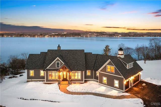 view of front of house with a garage, a chimney, and a water view