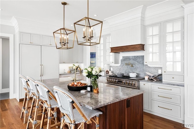 kitchen with light stone counters, dark wood finished floors, a kitchen island with sink, and double oven range