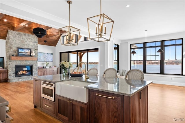 kitchen with lofted ceiling with beams, a sink, light wood-style floors, open floor plan, and a wealth of natural light