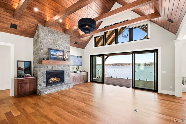 living room featuring beam ceiling, a fireplace, wood finished floors, and wooden ceiling