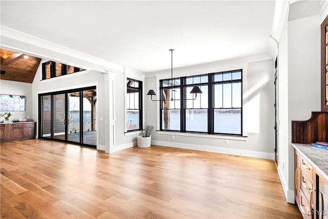 unfurnished dining area with vaulted ceiling, light wood-type flooring, and baseboards