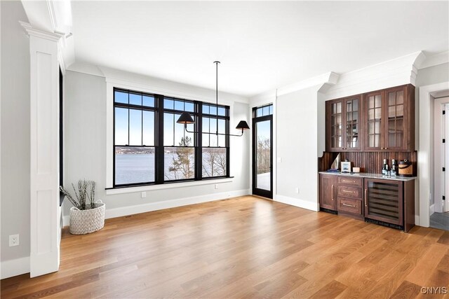 interior space featuring light wood-style floors, wine cooler, baseboards, and indoor bar