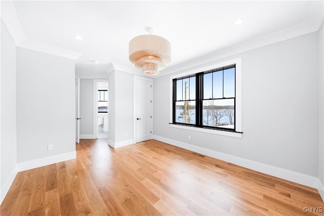 spare room featuring baseboards, crown molding, visible vents, and light wood finished floors