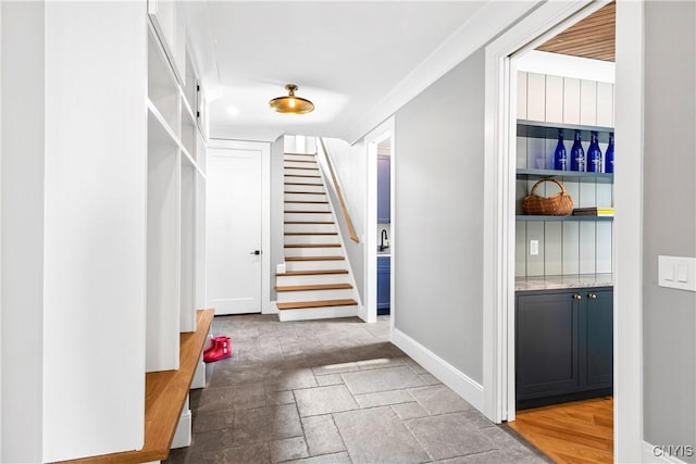 interior space with stone finish flooring, stairs, and baseboards