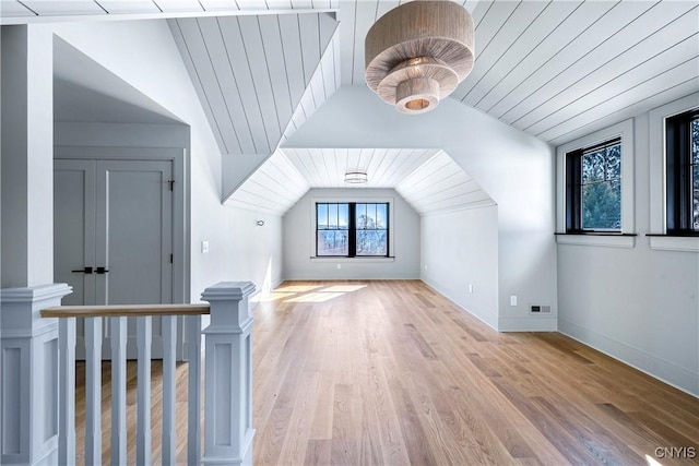 additional living space featuring baseboards, visible vents, vaulted ceiling, and wood finished floors