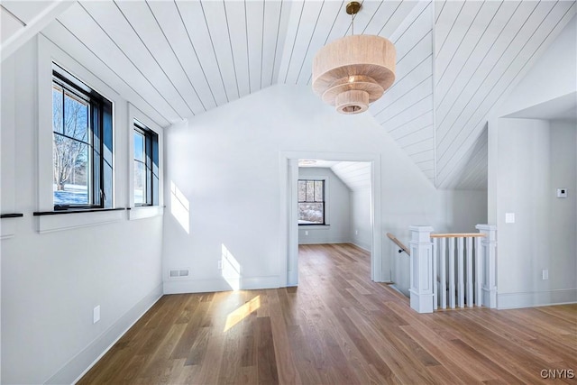 additional living space with visible vents, vaulted ceiling, baseboards, and wood finished floors