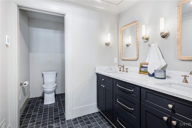 bathroom featuring double vanity, a sink, toilet, and baseboards