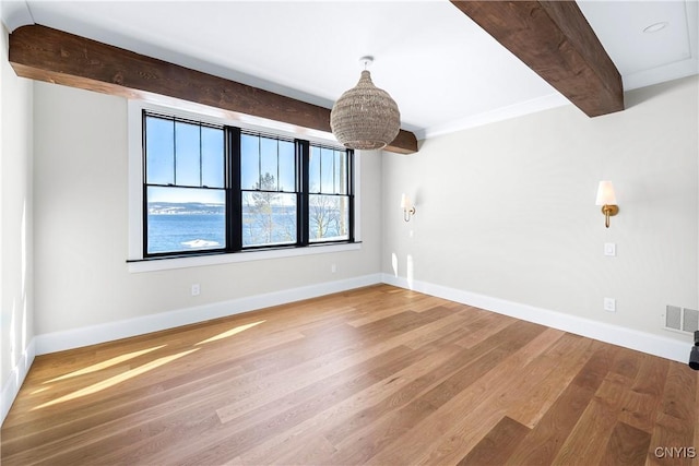 spare room featuring visible vents, light wood-type flooring, beam ceiling, and baseboards