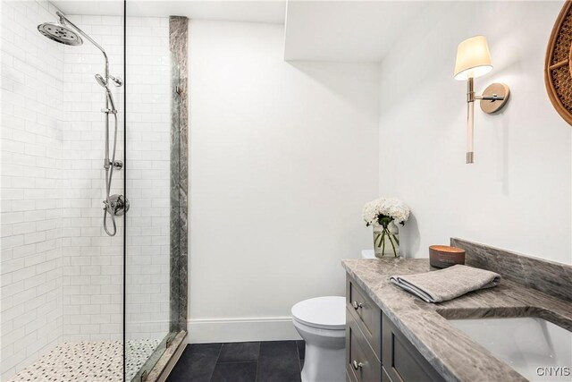 full bathroom featuring toilet, vanity, baseboards, a tile shower, and tile patterned floors