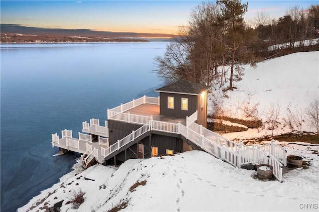 exterior space featuring an outbuilding, stairway, and a deck with water view