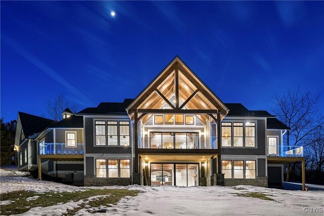 snow covered house with a balcony and stone siding