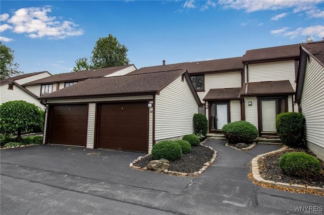 multi unit property featuring entry steps, a detached garage, and roof with shingles