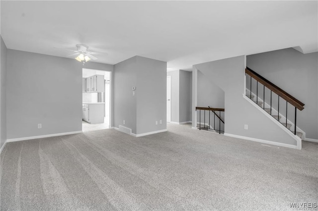 unfurnished living room with light carpet, ceiling fan, stairs, and baseboards