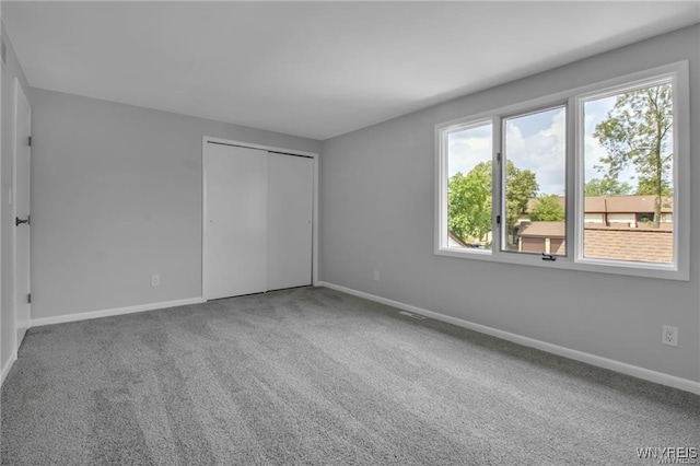 unfurnished bedroom featuring visible vents, a closet, baseboards, and carpet flooring