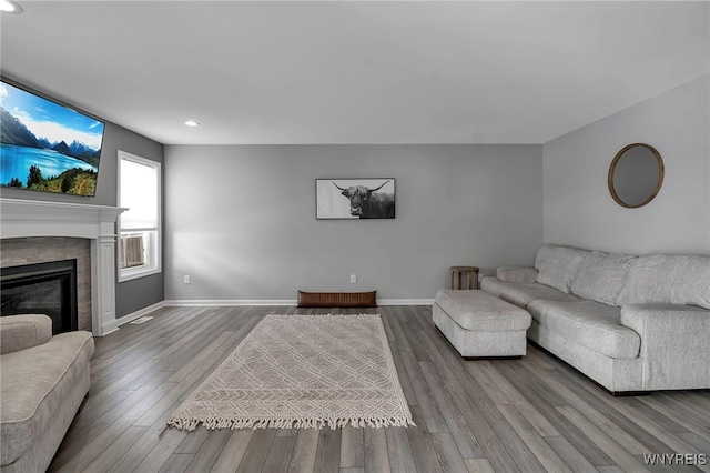 living area featuring recessed lighting, baseboards, a tiled fireplace, and wood finished floors