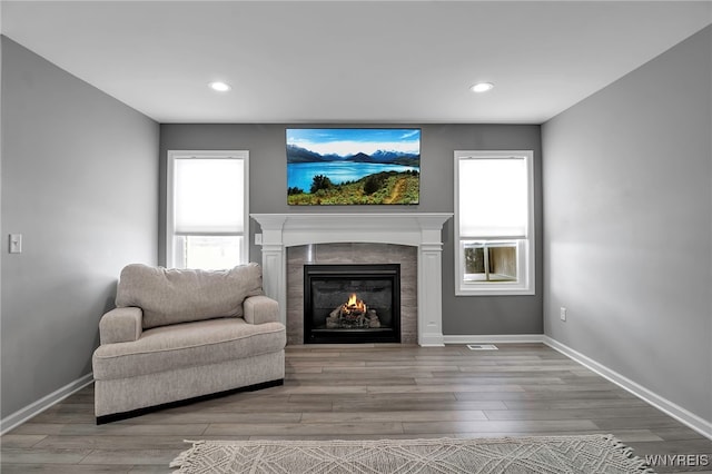 sitting room with wood finished floors, a tile fireplace, and a healthy amount of sunlight