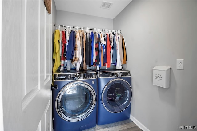 washroom featuring laundry area, separate washer and dryer, wood finished floors, visible vents, and baseboards