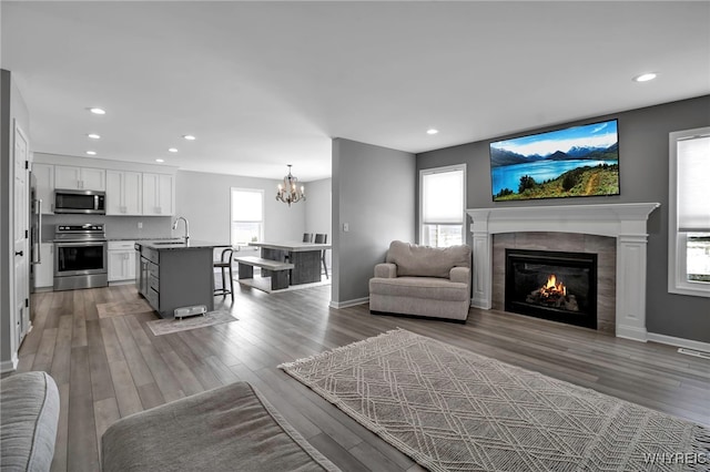 living room with baseboards, a tiled fireplace, wood finished floors, and recessed lighting