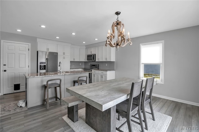 dining room featuring baseboards, a chandelier, wood finished floors, and recessed lighting