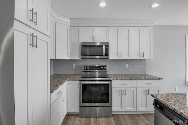 kitchen featuring appliances with stainless steel finishes, white cabinetry, light wood finished floors, and tasteful backsplash