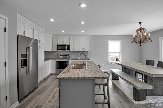 kitchen featuring white cabinets, appliances with stainless steel finishes, light wood-type flooring, a sink, and recessed lighting