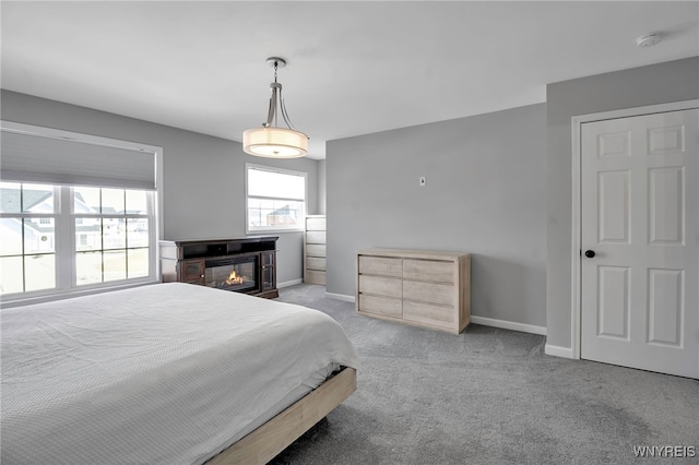 bedroom with carpet, a glass covered fireplace, and baseboards