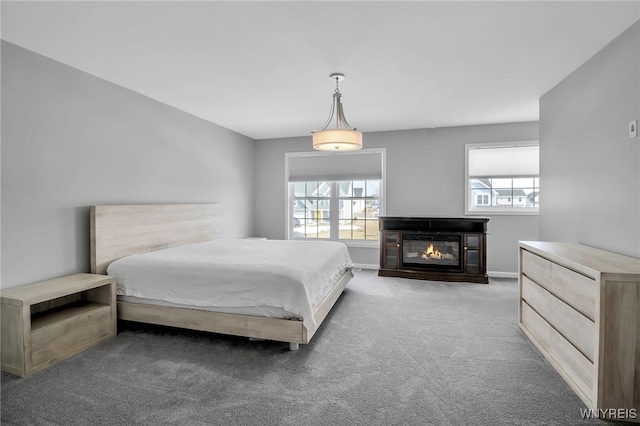 carpeted bedroom featuring a glass covered fireplace