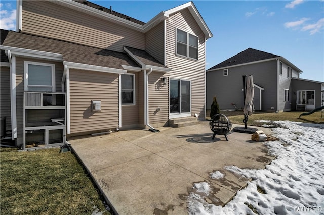 rear view of property with entry steps, roof with shingles, and a patio