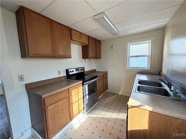 kitchen with stainless steel electric stove, light floors, a paneled ceiling, and a sink