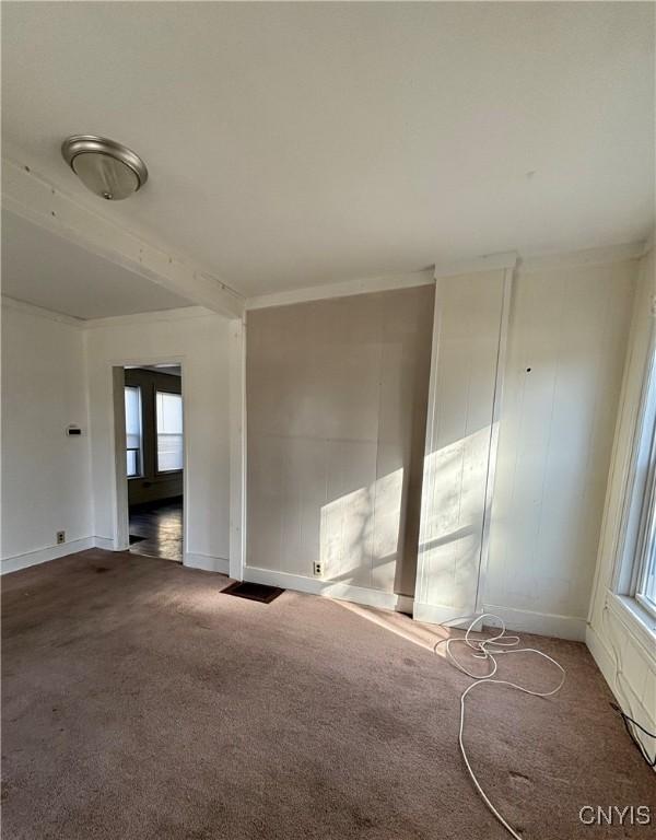 empty room with baseboards, carpet, and crown molding