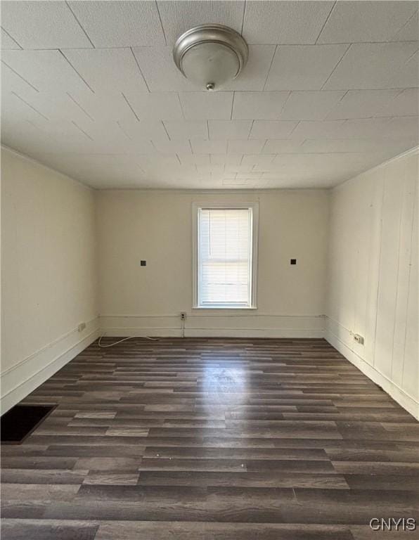 unfurnished room featuring baseboards and dark wood-style flooring