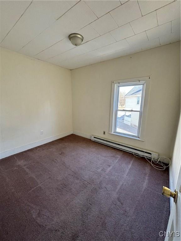 unfurnished room featuring baseboards, dark colored carpet, and a baseboard radiator