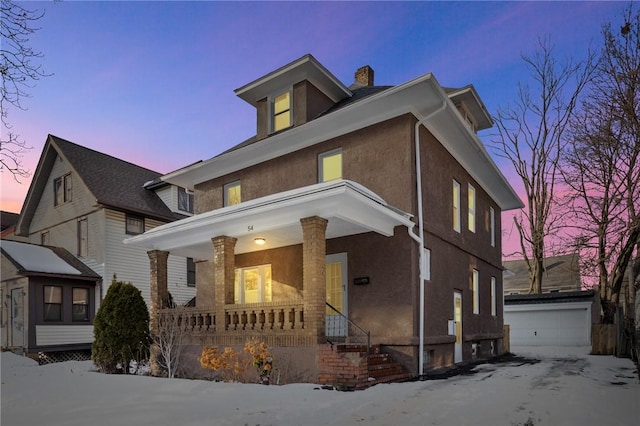 american foursquare style home with a garage, a chimney, covered porch, an outdoor structure, and stucco siding