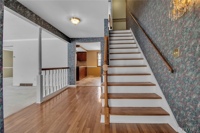 staircase with wallpapered walls, baseboards, wood finished floors, and beamed ceiling