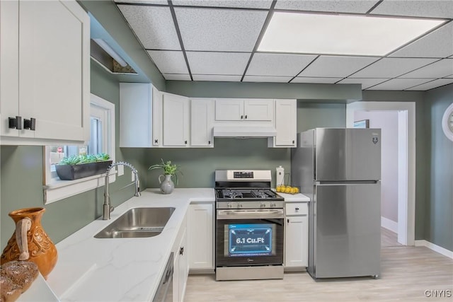 kitchen featuring under cabinet range hood, white cabinetry, appliances with stainless steel finishes, and a sink