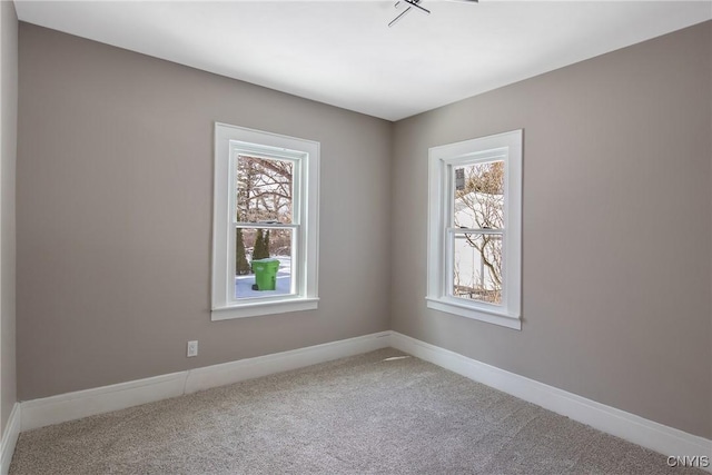 carpeted spare room featuring a wealth of natural light and baseboards