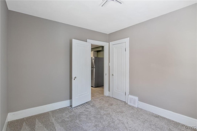 unfurnished room with light carpet, visible vents, and baseboards