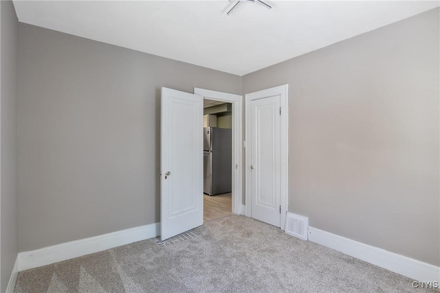 empty room featuring baseboards, visible vents, and carpet flooring