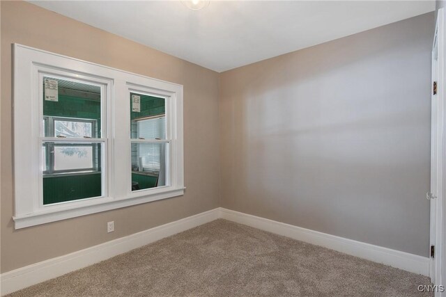carpeted spare room featuring baseboards