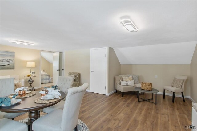 dining space with vaulted ceiling, wood finished floors, and baseboards