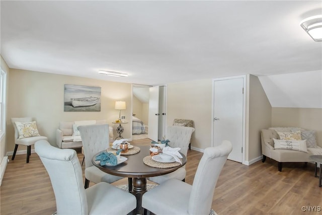 dining space with light wood-style flooring, baseboards, and vaulted ceiling