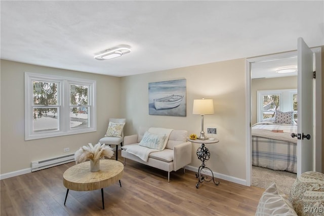 living area featuring a baseboard heating unit, baseboards, and wood finished floors
