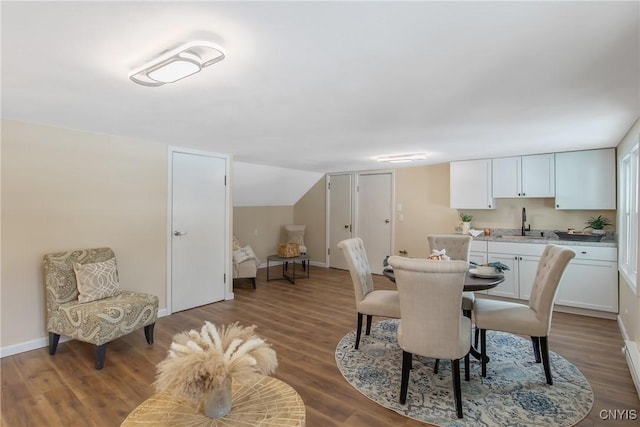 dining area featuring lofted ceiling, baseboards, and wood finished floors