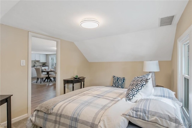 carpeted bedroom with baseboards, visible vents, and vaulted ceiling